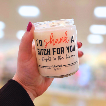 Hand holding a candle with text in a blurred indoor setting